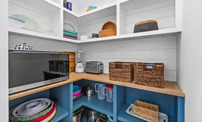 a kitchen with white and blue cabinets and baskets at Flamingo Key in Santa Rosa Beach