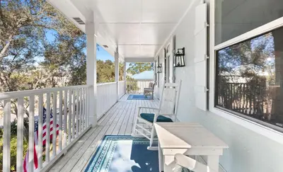 a white porch with a table and chairs on it at Flamingo Key in Santa Rosa Beach
