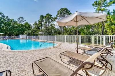 a swimming pool with chairs and an umbrella at Grove Getaway in Santa Rosa Beach