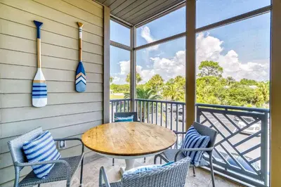 a porch with a table and chairs on a balcony at Grove Getaway in Santa Rosa Beach