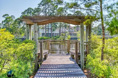 a wooden pergola with a bench on a wooden walkway at Seabourn in Santa Rosa Beach