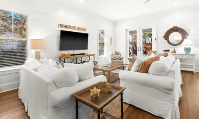 a living room with two white couches and a tv at The Sun Kiss in Santa Rosa Beach