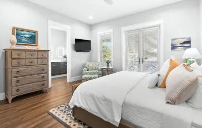 a bedroom with a bed and a chair and a television at The Sun Kiss in Santa Rosa Beach
