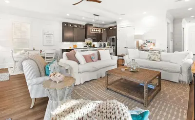 a living room with white furniture and a kitchen at The Sun Kiss in Santa Rosa Beach