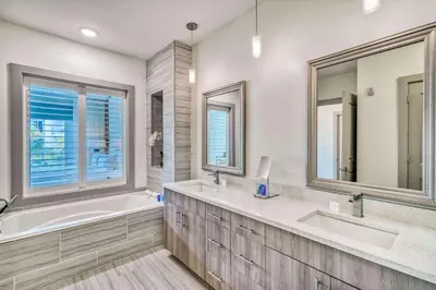 a bathroom with two sinks and a tub and two mirrors at Cabanas and Sunsets in Inlet Beach
