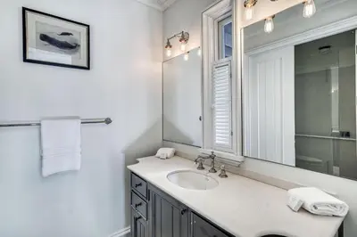 a white bathroom with a sink and a mirror at Rosemary Renaissance in Rosemary Beach