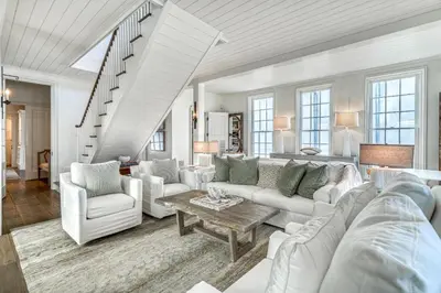 a living room with white furniture and a staircase at Rosemary Renaissance in Rosemary Beach