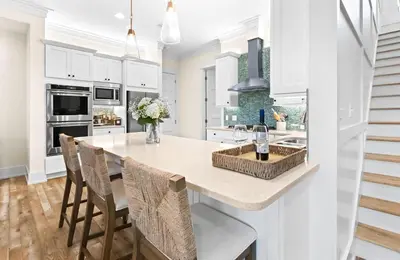 a kitchen with white cabinets and a kitchen island with chairs at Family Tides in Santa Rosa Beach
