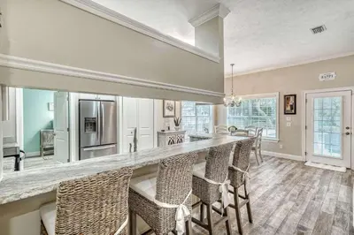 a kitchen with a bar with chairs and a counter top at Sandy's Seacrest in Inlet Beach