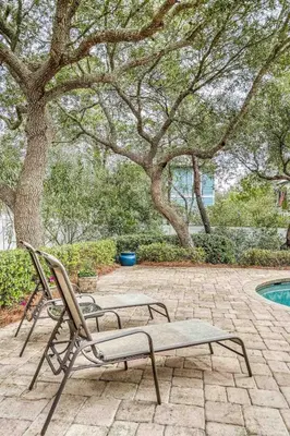 a patio with a chair and a bench next to a pool at Sandy's Seacrest in Inlet Beach