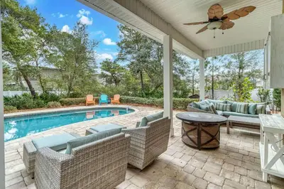 a patio with a pool and chairs and a ceiling fan at Sandy's Seacrest in Inlet Beach