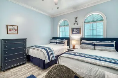 a bedroom with two beds and a dresser and two windows at Sandy's Seacrest in Inlet Beach