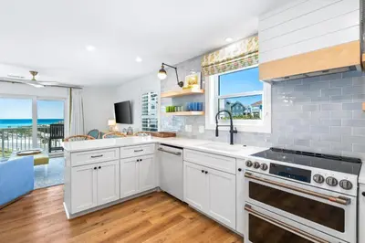 a kitchen with white cabinets and a view of the ocean at After Dune Delight in Santa Rosa Beach