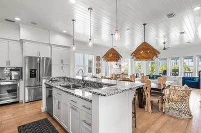 a kitchen and dining room with white cabinets and a large island at Sunshine and Fresh Air in Inlet Beach
