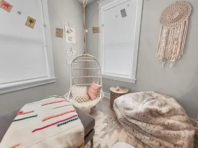 a room with a swinging chair and a ottoman at Daydream Believer (Seagrove) in Santa Rosa Beach