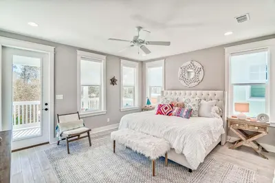 a bedroom with a bed and a chair and windows at Daydream Believer (Seagrove) in Santa Rosa Beach
