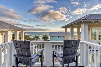 two chairs on a porch with a view of the ocean at Seas the Day in Santa Rosa Beach