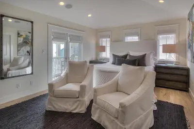 a bedroom with a bed and two white chairs at Seas the Day in Santa Rosa Beach