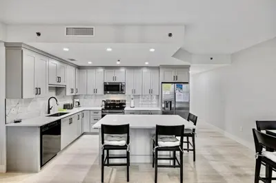 a kitchen with white cabinets and a table and chairs at Spectacular 1BD Resort Condo! Amazing Gulf Views! Free Beach Chairs! by Dolce Vita Getaways PCB in Panama City Beach