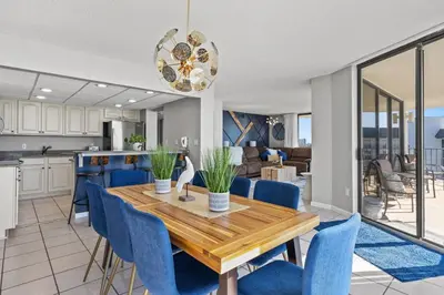 a kitchen and dining room with a wooden table and blue chairs at Edgewater Beach Resort - Tower I #1201 in Panama City Beach