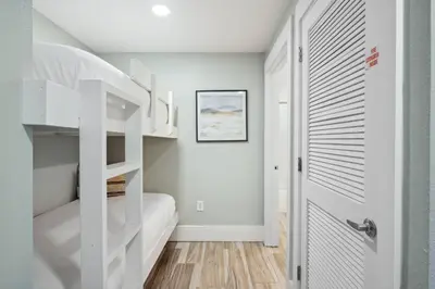 a bedroom with white bunk beds and a door at Laketown Wharf #137 by Nautical Properties in Panama City Beach