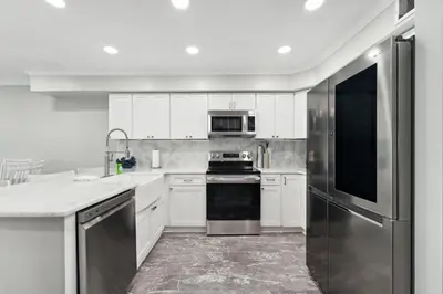 a kitchen with white cabinets and a stainless steel refrigerator at Dolphin View at 8629 Surf Drive by Nautical Properties in Panama City Beach