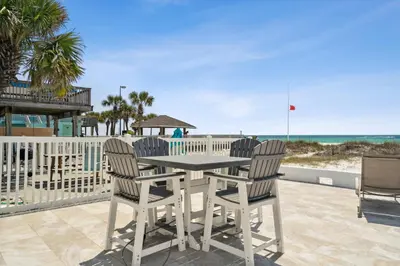 a table and chairs on a patio with the beach at Dolphin View at 8629 Surf Drive by Nautical Properties in Panama City Beach