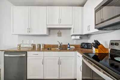a kitchen with white cabinets and a sink at Blissful Sunset at Laketown Wharf #1312 by Nautical Properties in Panama City Beach