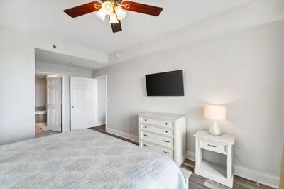 a white bedroom with a ceiling fan and a television at The Beach Is Calling at Laketown Wharf #1329 at Nautical Properties in Panama City Beach