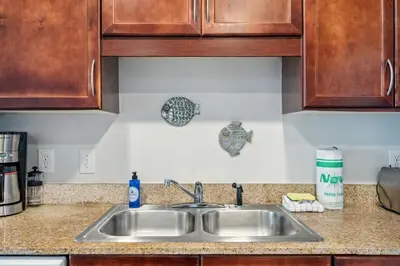 a kitchen counter with a sink and wooden cabinets at The Beach Is Calling at Laketown Wharf #1329 at Nautical Properties in Panama City Beach