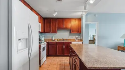 a kitchen with wooden cabinets and a white refrigerator at Nautical Breeze at Laketown Wharf #1911 by Nautical Properties in Panama City Beach