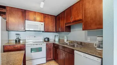 a kitchen with wooden cabinets and white appliances at Nautical Breeze at Laketown Wharf #1911 by Nautical Properties in Panama City Beach