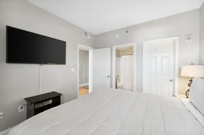 a white bedroom with a large bed and a flat screen tv at Laketown Wharf #638 by Nautical Properties in Panama City Beach