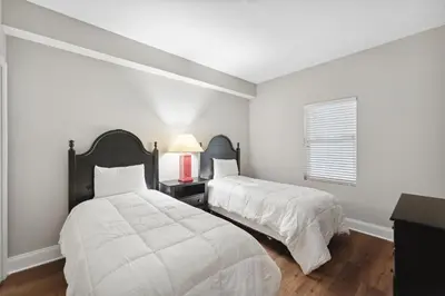 two beds in a bedroom with white walls and a window at Laketown Wharf #638 by Nautical Properties in Panama City Beach