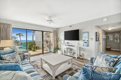a living room with blue furniture and a view of the ocean at Moondrifter #208 by Nautical Properties in Panama City Beach