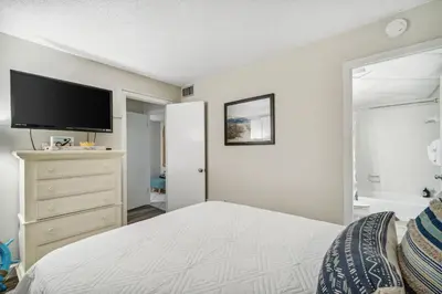 a bedroom with a bed and a flat screen tv at Moondrifter #208 by Nautical Properties in Panama City Beach