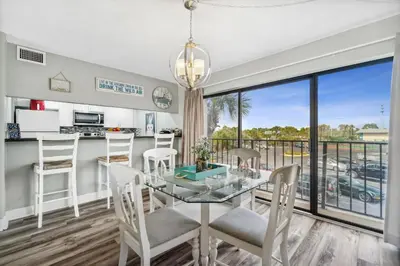 a dining room and kitchen with a glass table and chairs at Moondrifter #208 by Nautical Properties in Panama City Beach