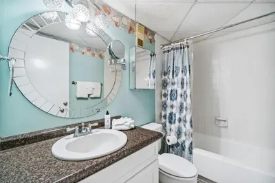 a bathroom with a sink and a toilet and a mirror at Moondrifter #208 by Nautical Properties in Panama City Beach
