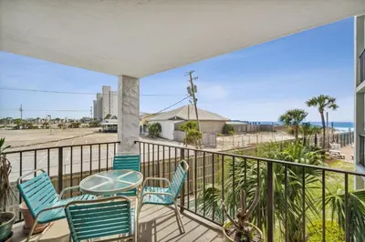 a balcony with chairs and a table and a view of the ocean at Moondrifter #208 by Nautical Properties in Panama City Beach