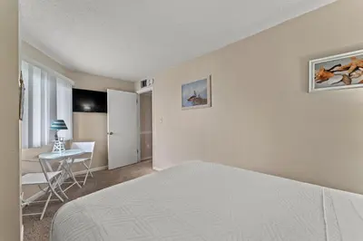 a bedroom with a bed and a desk and a table at Moondrifter #307 by Nautical Properties in Panama City Beach