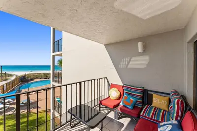 a balcony with a couch and chairs and a view of the beach at Moondrifter #307 by Nautical Properties in Panama City Beach