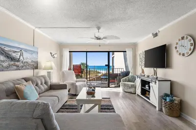 a living room with a couch and a tv at Moondrifter #307 by Nautical Properties in Panama City Beach