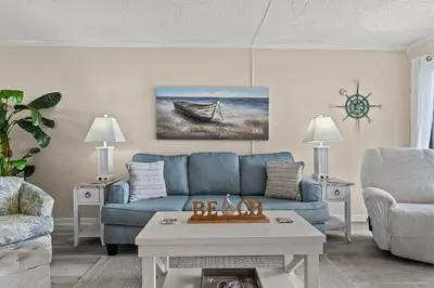 a living room with a blue couch and a table at Moondrifter #307 by Nautical Properties in Panama City Beach