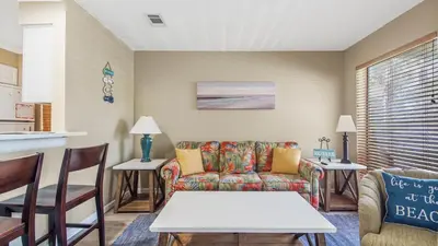a living room with a couch and a table at Nautical Watch #D4 by Nautical Properties in Panama City Beach