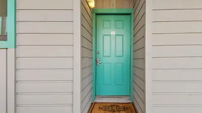 a green door on a house with white siding at Nautical Watch #D4 by Nautical Properties in Panama City Beach