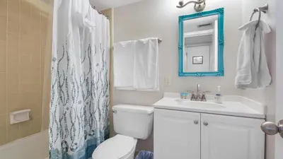 a bathroom with a toilet and a sink and a mirror at Sea Side Villas 118 by InJoy Vacations in Panama City Beach