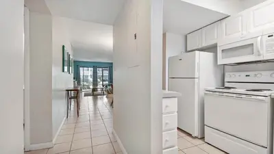 a white kitchen with white appliances and a hallway at Sea Side Villas 118 by InJoy Vacations in Panama City Beach