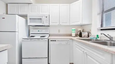 a white kitchen with white appliances and white cabinets at Sea Side Villas 118 by InJoy Vacations in Panama City Beach