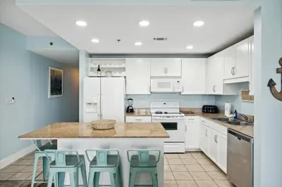 a kitchen with white cabinets and green stools at Laketown Wharf #828 by Nautical Properties in Panama City Beach
