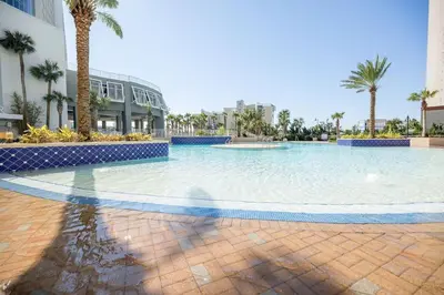 a large swimming pool with palm trees and a building at Laketown Wharf #828 by Nautical Properties in Panama City Beach